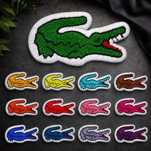 May include: A collection of embroidered crocodile patches in various colors including green, orange, yellow, light blue, brown, red, pink, magenta, blue, dark blue, lavender, and purple, each featuring a white border and red mouth detail.