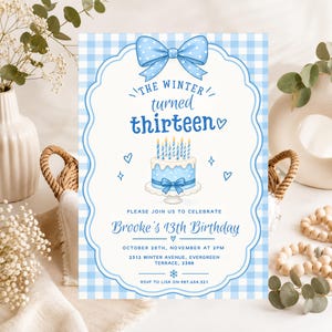 Puede incluir: Una tarjeta de invitación de cumpleaños rectangular con un borde de cuadros vichy azul claro y blanco, con un gran lazo azul en la parte superior. El texto dice: THE WINTER turned thirteen, Brooke's 13th Birthday, October 20th, November at 2pm, 2312 Winter Avenue, Evergreen Terrace, 2388, RSVP to Lisa on 987.654.321. Un pastel azul con velas está centrado.
