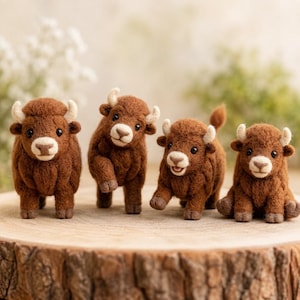 May include: Four needle-felted brown bison figurines with cream-coloured horns and muzzles. Each bison has a textured wool finish, small black eyes, and distinct postures, including standing, walking, and sitting, arranged in a row on a wooden surface.