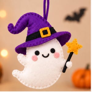 May include: A felt ghost ornament featuring a purple witch hat with a black band and yellow buckle. The white ghost has black eyes, a smiling mouth, pink cheeks, and holds a yellow star wand on a black stick. A purple loop is attached for hanging.