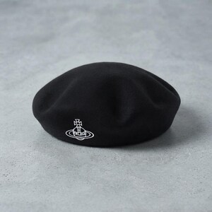 May include: A solid black beret featuring a white embroidered orb logo on the front. The orb design consists of a cross atop a sphere surrounded by a ring. The hat has a smooth, rounded crown and a soft, felted texture throughout the entire surface.