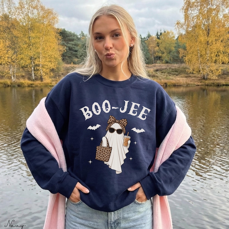 May include: A navy blue crewneck sweatshirt featuring a white graphic of a ghost wearing a leopard print bow and sunglasses, holding a leopard print tote bag and a coffee cup. The text BOO-JEE is printed above the ghost with small bats and stars.