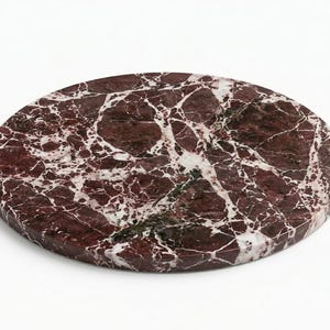 May include: A circular slab of deep burgundy marble featuring a complex network of white and light gray veining throughout the surface. The stone has a smooth, polished finish with a consistent thickness and a flat, rounded edge profile.