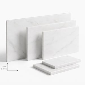 May include: A set of five rectangular white marble boards with grey veining, arranged in a tiered display. Three boards stand vertically in a row, while two smaller boards lie flat in front. Each board has a thickness of 0.79 inches.