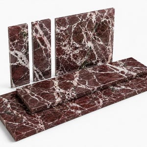 May include: A collection of five rectangular marble tiles featuring a deep burgundy red base color with prominent, intricate white veining throughout. The set includes three upright vertical tiles of varying widths and two horizontal tiles.
