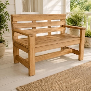Puede incluir: Un banco de madera de color marrón claro con respaldo de listones, asiento de listones planos y patas cuadradas robustas con reposabrazos. El banco está construido con tablones horizontales de madera natural con veta visible.