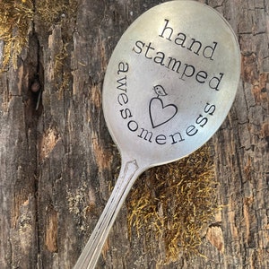 May include: A silver spoon with the words "hand stamped awesomeness" engraved on it. A small heart with a bird inside is also engraved on the spoon.