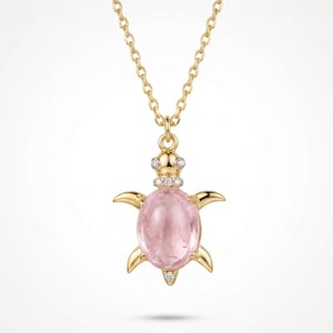 May include: A gold necklace featuring a turtle-shaped pendant. The turtle has a smooth, oval-shaped pink gemstone as its shell, with small clear stones set into the head, neck, and tail. The pendant hangs from a delicate gold chain.