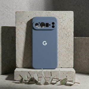 Peut inclure: Une coque de smartphone bleu ardoise mat avec une découpe horizontale proéminente pour l'appareil photo en haut et un logo G blanc centré. La protection présente une finition lisse et unie avec des ouvertures précises pour les objectifs.