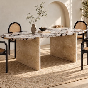 Può includere: Un tavolo da pranzo ovale con piano in marmo bianco e marrone scuro, sostenuto da due spesse basi curve in pietra travertino beige. Il tavolo è circondato da quattro sedie in legno nero con schienali arrotondati e sedute in paglia di Vienna.