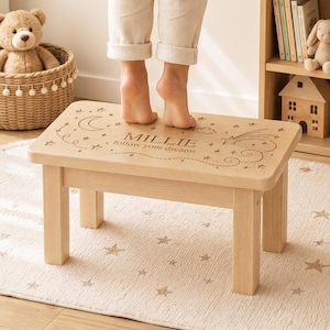 May include: A light-coloured wooden step stool featuring a laser-engraved design on the top surface. The engraving includes a crescent moon, stars, a shooting star, and the text "MILLIE follow your dreams" in a clear, centred font.