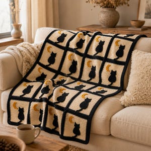 Peut inclure: Une couverture en crochet présentant un motif répétitif de carrés couleur crème, chacun orné d'une silhouette de chat noir et d'un petit croissant de lune jaune. Les carrés sont bordés de fil noir épais, créant un design géométrique structuré.