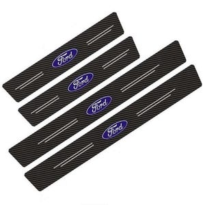 Op de afbeelding: Een set van vier rechthoekige deurdrempelbeschermers met een zwarte koolstofvezeltextuur. Elk stuk toont het blauw-witte Ford-logo in het midden, vergezeld van twee dunne, parallelle witte horizontale lijnen aan weerszijden van het logo.