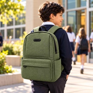 May include: A sage green backpack with a textured fabric finish, featuring a large main compartment, a front zipped pocket with a small black ring attachment, and side pockets. The bag has black zips and a rectangular black logo patch on top.