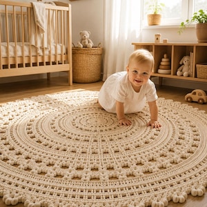 May include: A large, circular, cream-colored crochet rug featuring an intricate, textured pattern with concentric rings of raised stitches, small openwork squares, and a scalloped, decorative border edge made of thick, soft yarn.