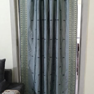 Peut inclure: Un panneau de rideau bleu ardoise doté d'une bordure décorative verticale de chaque côté avec un motif géométrique blanc et vert foncé. Le tissu principal présente un léger éclat et est orné de petits motifs de feuilles brodés et espacés.