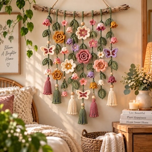 May include: A wall hanging featuring multiple strands of crocheted flowers, leaves, and butterflies suspended from a piece of driftwood. The arrangement includes pink, yellow, white, and purple blossoms, green foliage, and tassels in various colours.