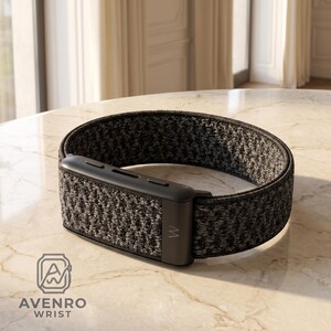 May include: A black and grey heathered fabric watch band featuring a solid black rectangular connector piece with a small letter W logo. The band has a textured, woven appearance and is displayed in a circular shape with a logo reading AVENRO WRIST.