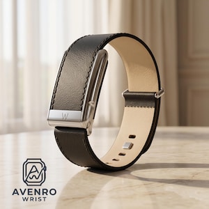 May include: A dark brown leather wristband featuring a silver-toned metallic rectangular housing with the letter W engraved on the front. The band has a smooth beige interior lining, silver-toned buckle hardware, and visible stitching along the edges.