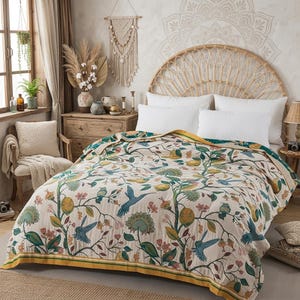 May include: A cream-colored bedspread featuring a repeating pattern of green leafy branches, yellow lemons, and blue hummingbirds. The textile has a yellow border trim and is draped over a bed with white pillows and a curved rattan headboard.