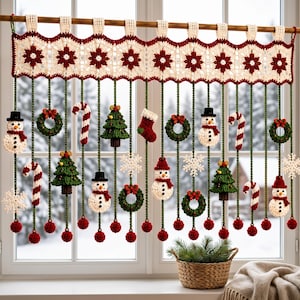 May include: A cream-coloured crocheted valance with a red floral pattern hangs from a wooden rod. Green yarn strands dangle from the valance, each featuring crocheted Christmas ornaments including snowmen, candy canes, trees, wreaths, and snowflakes.