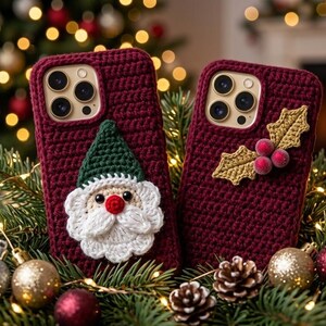 May include: Two dark red crochet phone cases. One case features a crocheted Santa Claus face with a green hat, white beard, and red nose. The other case features a crocheted holly leaf and berry appliqué. Both cases have cutouts for camera lenses.