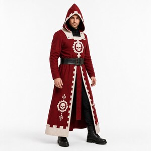 Pu&ograve; includere: Una lunga tunica con cappuccio color rosso scuro, caratterizzata da bordi color crema e un emblema bianco a forma di ingranaggio con un teschio al centro. L'indumento include una cintura nera con fibbia, indossata su pantaloni e stivali neri.
