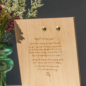 May include: A wooden plaque with a handwritten message on it. The message reads "Happy 5th anniversary, my love! We've built an amazing life together these past five years. You make every day feel special with your kindness, curiosity, and goofiness. No matter what challenges have come our way, knowing that we will figure it out together gives me so much comfort. Thank you for being you and for everything you do, Andrew. These five years have been so fulfilling. I can only imagine what our future holds! I am so excited to grow old with you. Love, Emily."