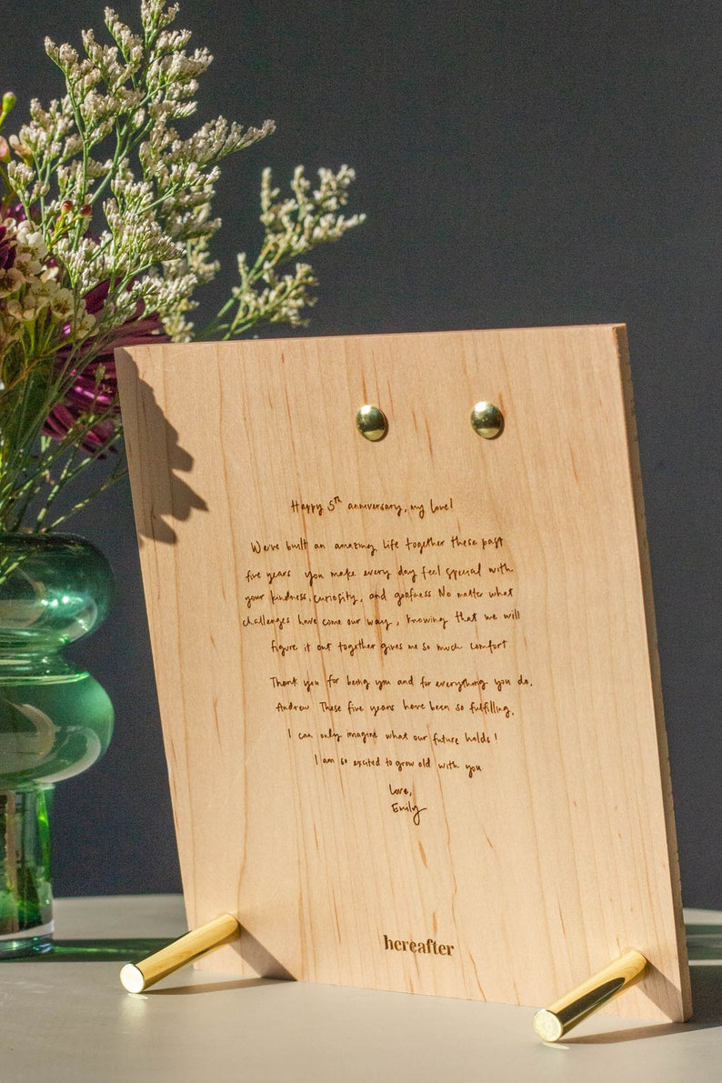 May include: A wooden plaque with a handwritten message on it. The message reads "Happy 5th anniversary, my love! We've built an amazing life together these past five years. You make every day feel special with your kindness, curiosity, and goofiness. No matter what challenges have come our way, knowing that we will figure it out together gives me so much comfort. Thank you for being you and for everything you do, Andrew. These five years have been so fulfilling. I can only imagine what our future holds! I am so excited to grow old with you. Love, Emily."