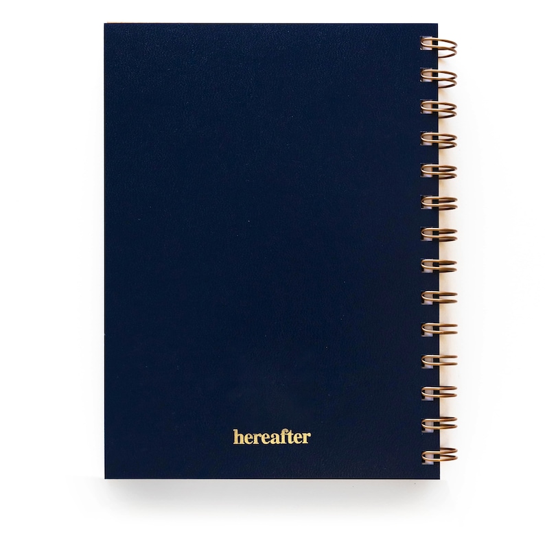 May include: A dark blue spiral bound notebook with the word "hereafter" printed in gold on the front cover.