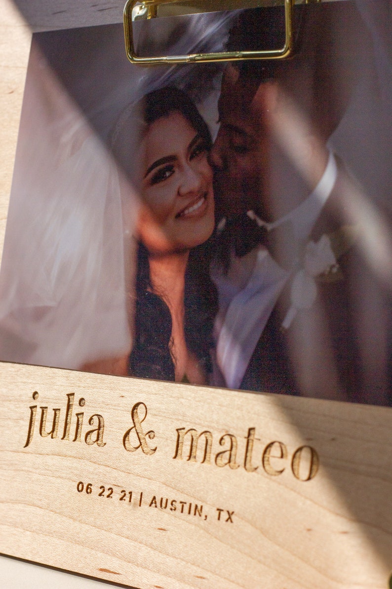 May include: A wooden photo frame with a picture of a couple. The frame is engraved with the text "julia & mateo" and the date "06 22 21 | AUSTIN, TX".