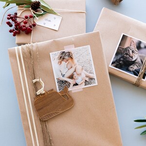 May include: A brown paper gift wrapped with twine and a wooden whale ornament that says "Love you a ton!" A photo of a mother and child is attached to the gift with tape.