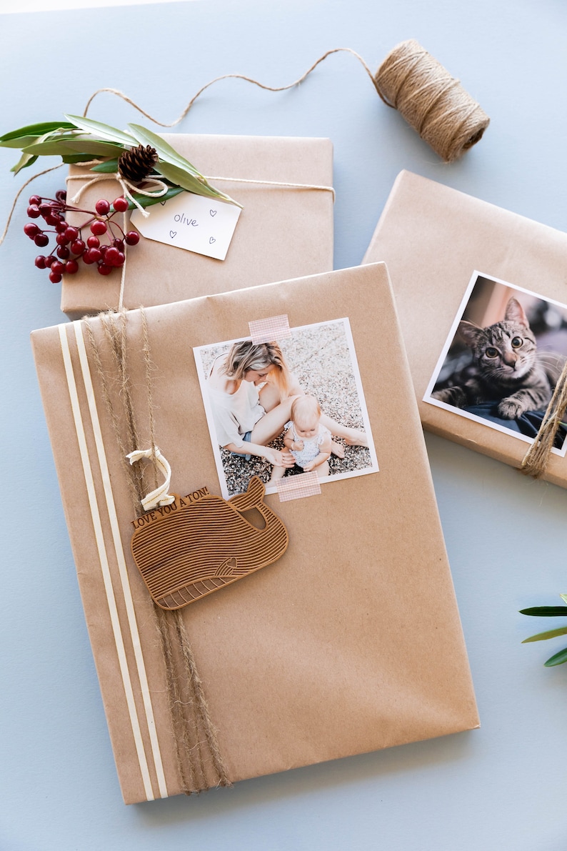 May include: A brown paper gift wrapped with twine and a wooden whale ornament that says "Love you a ton!" A photo of a mother and child is attached to the gift with tape.