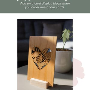 May include: A wooden card display stand with a geometric heart design. The stand is made of natural wood and has a simple, elegant design.