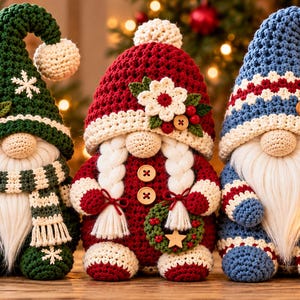 Op de afbeelding: Drie gehaakte kabouterfiguren met witte garen baarden en mutsen met pompons. De linker kabouter is groen met sneeuwvlokken, de middelste is rood met witte vlechten en een krans, en de rechter is blauw met een kleine lantaarn als accessoire.