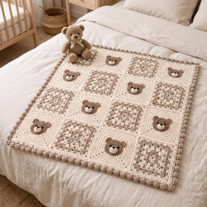 Könnte beinhalten: Eine quadratische Häkeldecke mit abwechselnden cremefarbenen und beigen Granny-Squares sowie Quadraten mit applizierten braunen Bärengesichtern. Die Decke hat einen gewellten Rand und wird von einem kleinen braunen Teddybären begleitet.