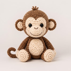 May include: A crocheted monkey stuffed animal featuring dark brown yarn for the body, limbs, and tail, with light cream-coloured yarn detailing on the face, ears, chest, and feet. The monkey has black plastic eyes and a small tuft of brown yarn on top.