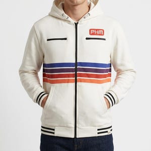 May include: An off-white zip-up hoodie featuring a black front zipper, two chest pockets with black zippers, and a horizontal stripe pattern in blue, purple, red, and orange. A rectangular red patch with the white text PHM is on the chest.