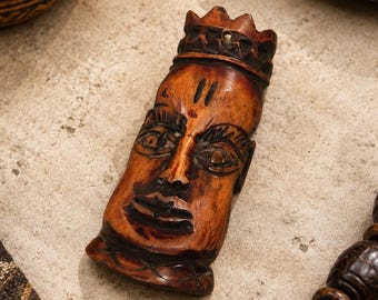 Pingente grande com rosto africano feito de osso, medindo 102 x 39 mm.