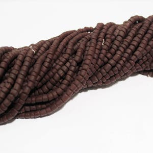 May include: A strand of dark brown beads, made of a smooth, matte material. The beads are small and cylindrical, and they are strung together in a long, continuous strand.
