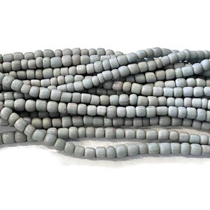 May include: A strand of light gray seed beads. The beads are small and round, and they are strung together on a thin thread.