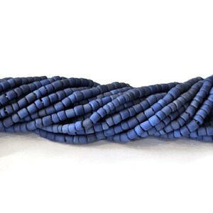 May include: A strand of blue glass beads, each bead is a small, square shape.