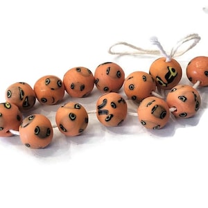 May include: A strand of orange beads with black and yellow designs. The beads are strung on a white cord.