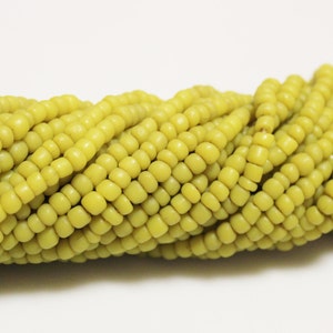 May include: A strand of small, round, matte green glass beads. The beads are uniform in size and shape, and they are strung together in a continuous strand.