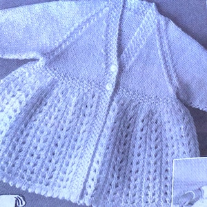 May include: A light blue knitted baby cardigan with a button fastening and a delicate lace pattern.