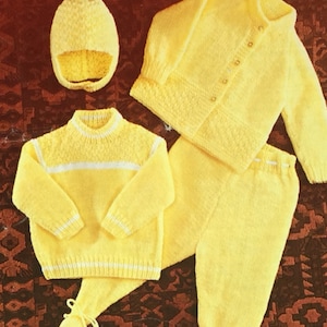 Puede incluir: Un conjunto de ropa de bebé de punto en color amarillo brillante. El conjunto incluye un gorro, una rebeca con botones, una camiseta de manga larga y un pantalón. La camiseta y la rebeca tienen detalles blancos.