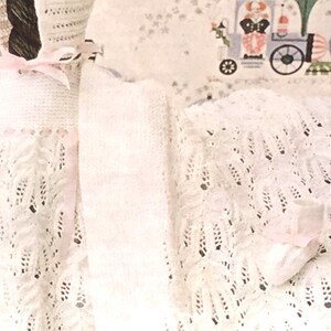 Pode incluir: Um conjunto de vestido, gorro e sapatinhos para bebé em crochê branco. O vestido tem 46 cm de comprimento, o gorro 28 cm de circunferência e os sapatinhos são de tamanho médio.