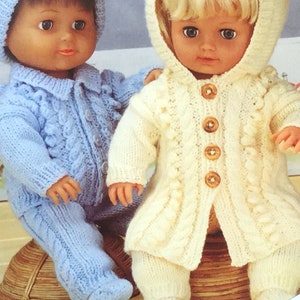 May include: Two knitted doll outfits, one in light blue and one in cream. The outfits feature cable knit patterns and button closures. The dolls are not included.