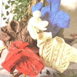 May include: Five knitted cardigans in different colors and patterns. The cardigans are brown, red, white, blue, and cream. They are all made with a cable knit stitch.