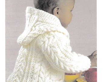 May include: A white knitted baby cardigan with a hood and cable knit pattern.